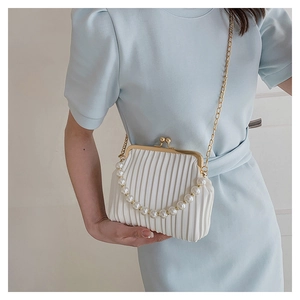 White pleated shell handbag with pearl handle and gold chain worn by a model