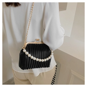 Detailed view of black pleated shell bag featuring pearl handle and gold chain strap