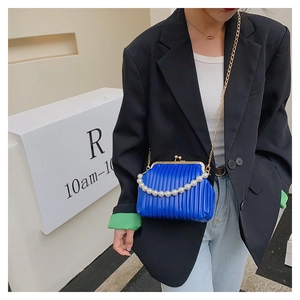 Detail of blue pleated shell bag with pearl handle and metal chain on model