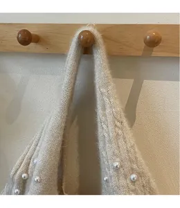 Detail of cream knitted tote strap with thick braided texture and white pearl accents