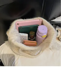 Top view of large white plush bucket bag showing spacious interior with tablet and items