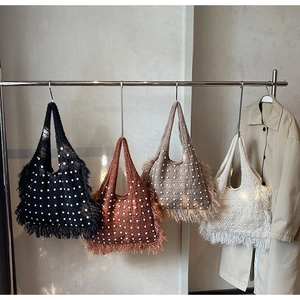 Detail of knit tote bags with pearls and long tassels in black brown and cream colors