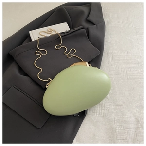 Detail of light green pebble evening clutch with golden snake chain on blazer