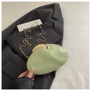 Detail of pea green oval evening clutch with gold metal clasp and snake chain on blazer