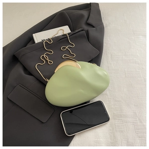 Macro view of light green cloud bag with gold metal handle and chain against a suit