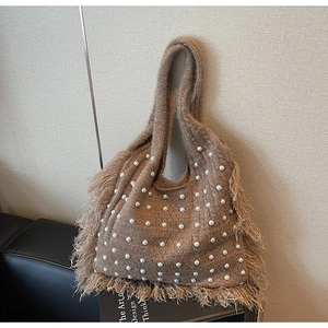 Detail of brown knit tote bag with white pearl embellishments and fringe trim