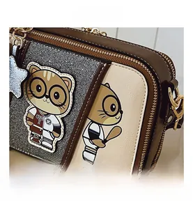 Close-up of baseball cartoon patch and chain strap on crossbody camera bag