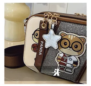 Close-up of stylish contrast crossbody bag showing leather panda zipper pull and star charm