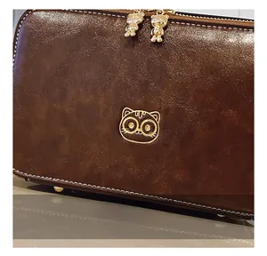 Detail view of brown vintage camera bag showing the leather texture and bear charms