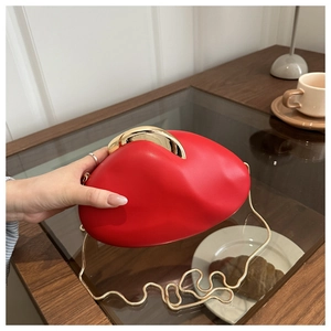 Close-up of red irregular acrylic evening bag with gold chain strap on coffee table