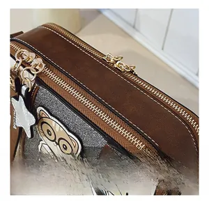Detail view of bold stitching and premium gold double zipper on a contrast crossbody bag