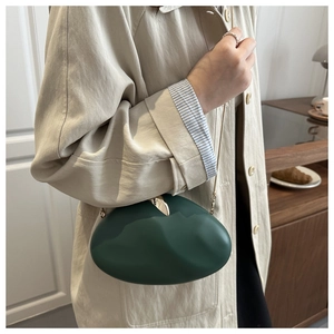 Macro detail of dark green oval acrylic bag with matte texture and gold metal clasp