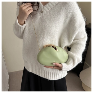 Detail of light green pebble-shaped acrylic clutch with polished gold clasp and chain strap
