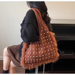 Detail of caramel knit shoulder bag featuring faux pearls and bohemian fringe tassels