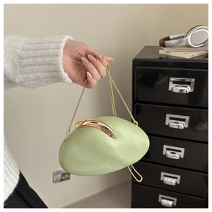 Detail of light green oval acrylic handbag with gold curved clasp and fine chain strap