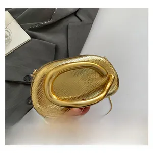 Detailed close-up of a gold snake-textured box bag with a unique C-shaped metal handle