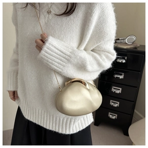 Macro detail of oval acrylic evening bag with gold chain and matte pearl texture