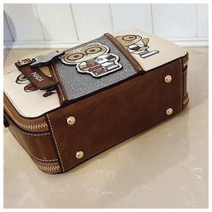 Detail view of the brown leather bottom with golden protective feet on a cartoon bag