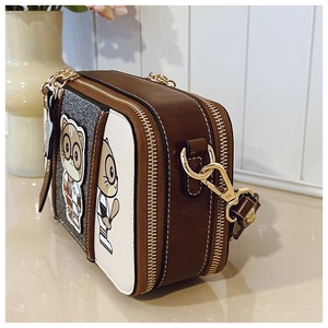 Detail of camera-style crossbody bag with cartoon cat print and gold-tone zippers