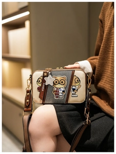 Detail of crossbody camera bag featuring cartoon cats and contrast color stitching