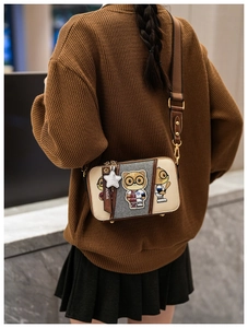 Detail of crossbody bag featuring cartoon panda embroidery and brown nylon strap
