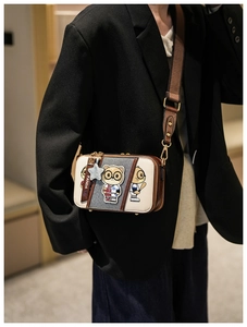 Detail of cartoon cat graphics on contrast color crossbody bag with wide strap