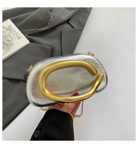 Detail of silver snake-pattern bag with matte gold C-shaped handle and metal chain