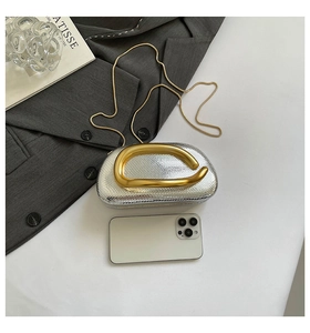 Detail view of silver snake-pattern clutch bag with unique gold metallic handle and chain