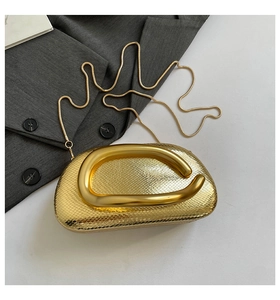Close-up of golden snakeskin texture and metallic C-shaped handle on luxury evening bag