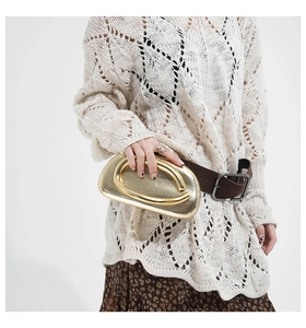 Detail of gold snake-textured wristlet bag with U-shaped metal handle on model