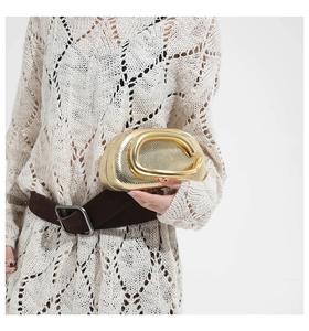 Detailed view of a gold snakeskin textured clutch featuring a large C-shaped metal handle