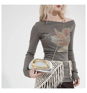 Detail of silver metallic purse with large gold hardware and chain strap on model