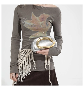 Detail of silver snake-pattern clutch with a bold gold circular metal handle