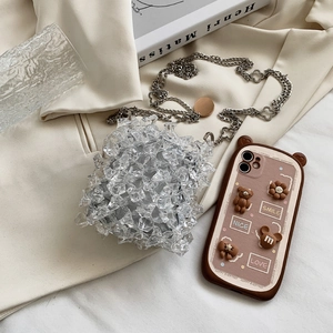 Mini acrylic crystal chain bag and cartoon phone case on aesthetic silk background