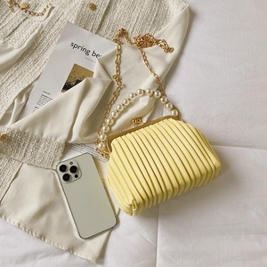Elegant yellow pleated shell bag with pearl handle and gold chain strap in 45-degree view
