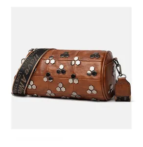Vue détaillée d'un sac cylindrique marron avec rivets hexagonaux et bandoulière large