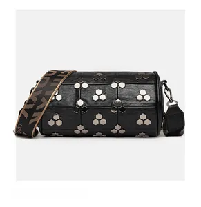 Détail du sac cylindrique noir avec rivets hexagonaux argentés et large sangle tissée