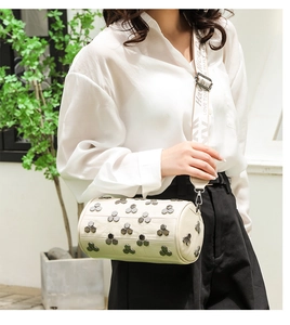 Détail du sac cylindre blanc cassé avec rivets hexagonaux et large bandoulière