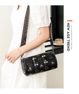 Détail du sac cylindrique noir avec rivets hexagonaux argentés et bandoulière large