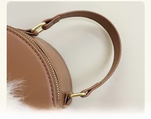 Detail of soft brown leather handle with golden metal hardware and plush white trim