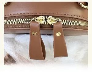 Detailed close-up of custom dual brass zippers on the textured brown leather bag