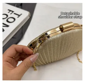 Dettaglio della borsa a mano dorata con paillettes, trama a conchiglia e catena