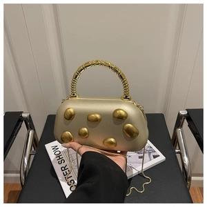 Champagne harde clutch met gouden ovale metalen versieringen en een ringhandvat