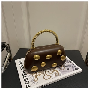 Detailopname van bruine lederen tas met gouden accenten en sculpturaal metalen handvat
