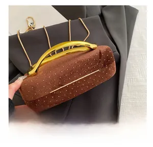 Detailed view of brown velvet evening clutch with gold dot pattern and metal handle
