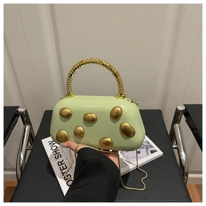 Detail van lichtgroene box-tas met goudkleurige studs en kralenhandvat op stoel