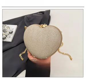 Detail of champagne gold heart clutch bag with glitter texture and chain strap