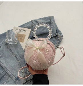 Detail of pink plush ball bag with transparent beaded handle and satin ribbon bow decoration