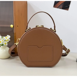 Detail of round brown plush PU leather crossbody bag with golden hardware and dual zippers