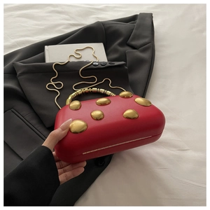 Detail van rode halfronde clutch met matgouden noppen en een kralen handvat